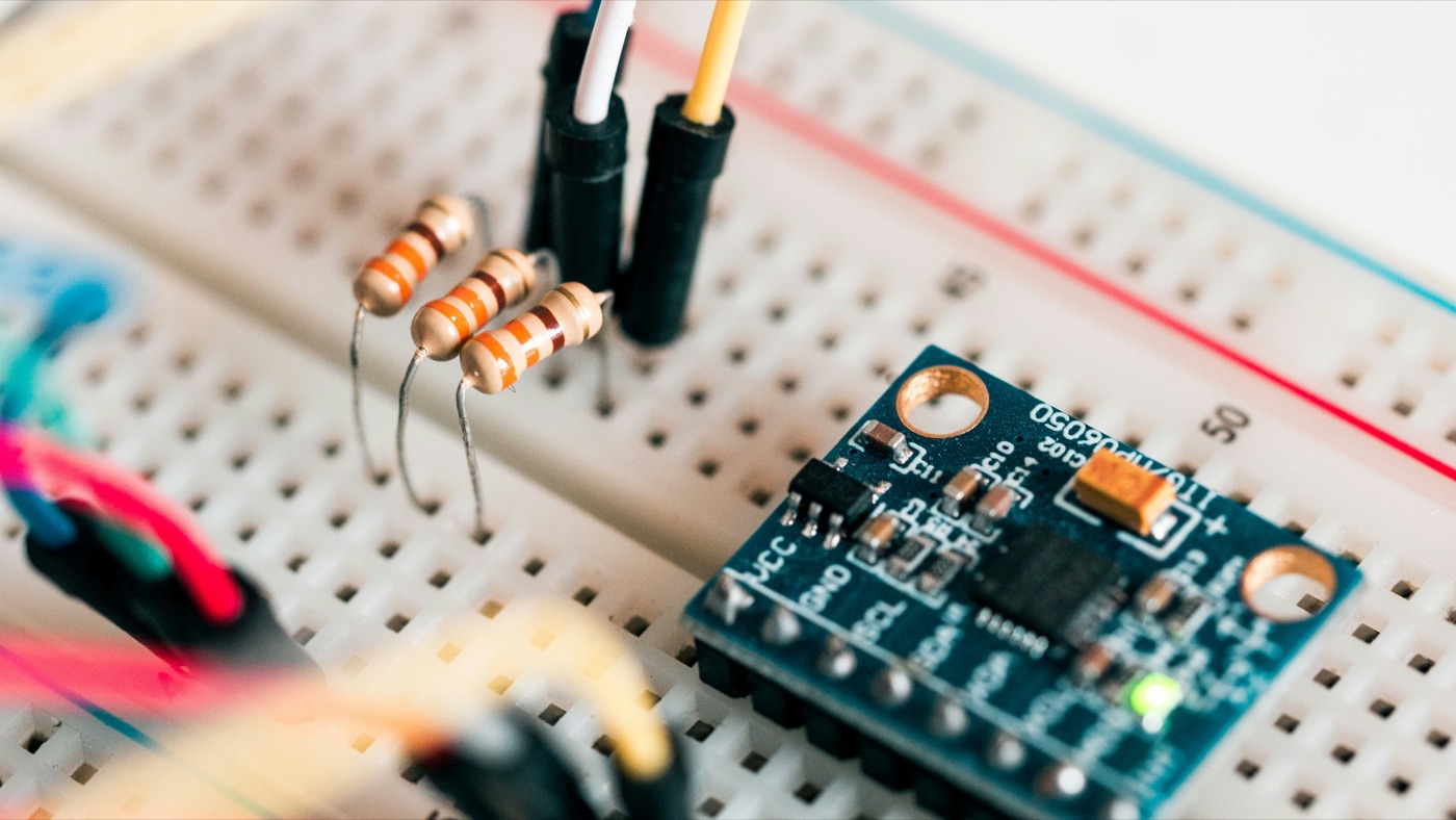 Individual maker's bench: a breadboard with a sensor module and resistors, hand-wired in colored jumper wires.